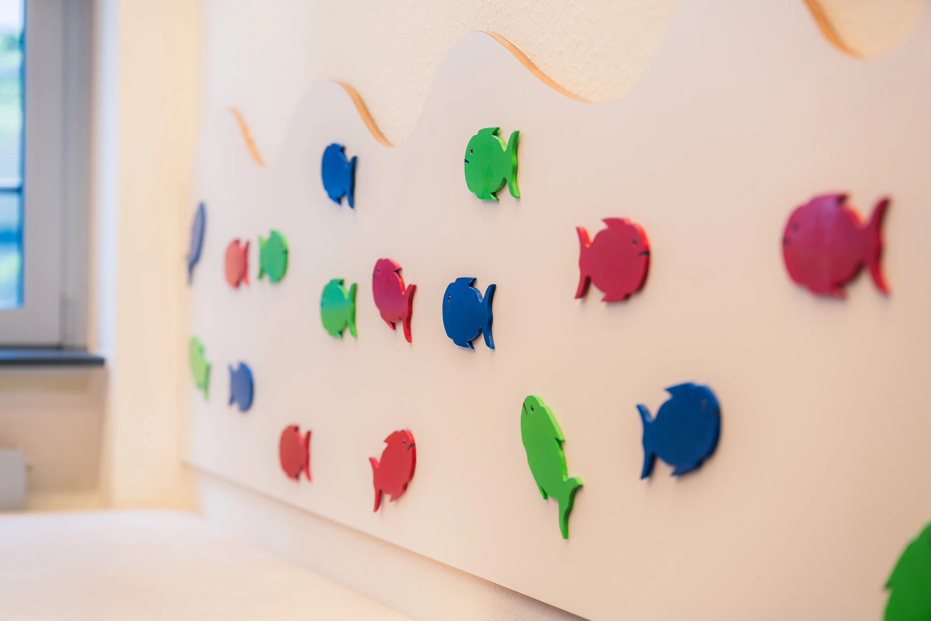 Bunte Holzfische an der Wand des Wartezimmers