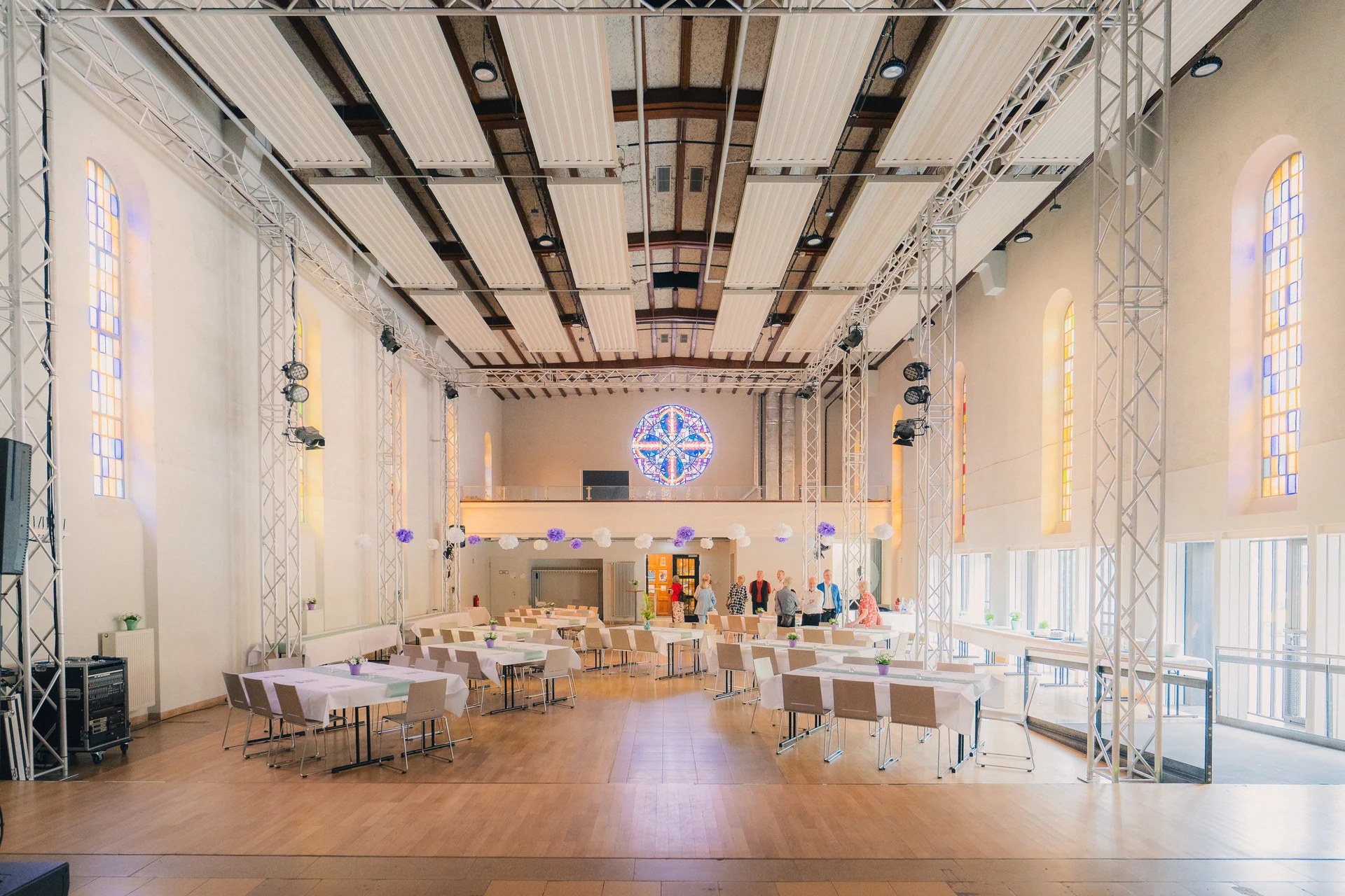 Der leere Festsaal der Chapel mit gedeckten Tischen, Kirchenfenstern und Lichttraversen