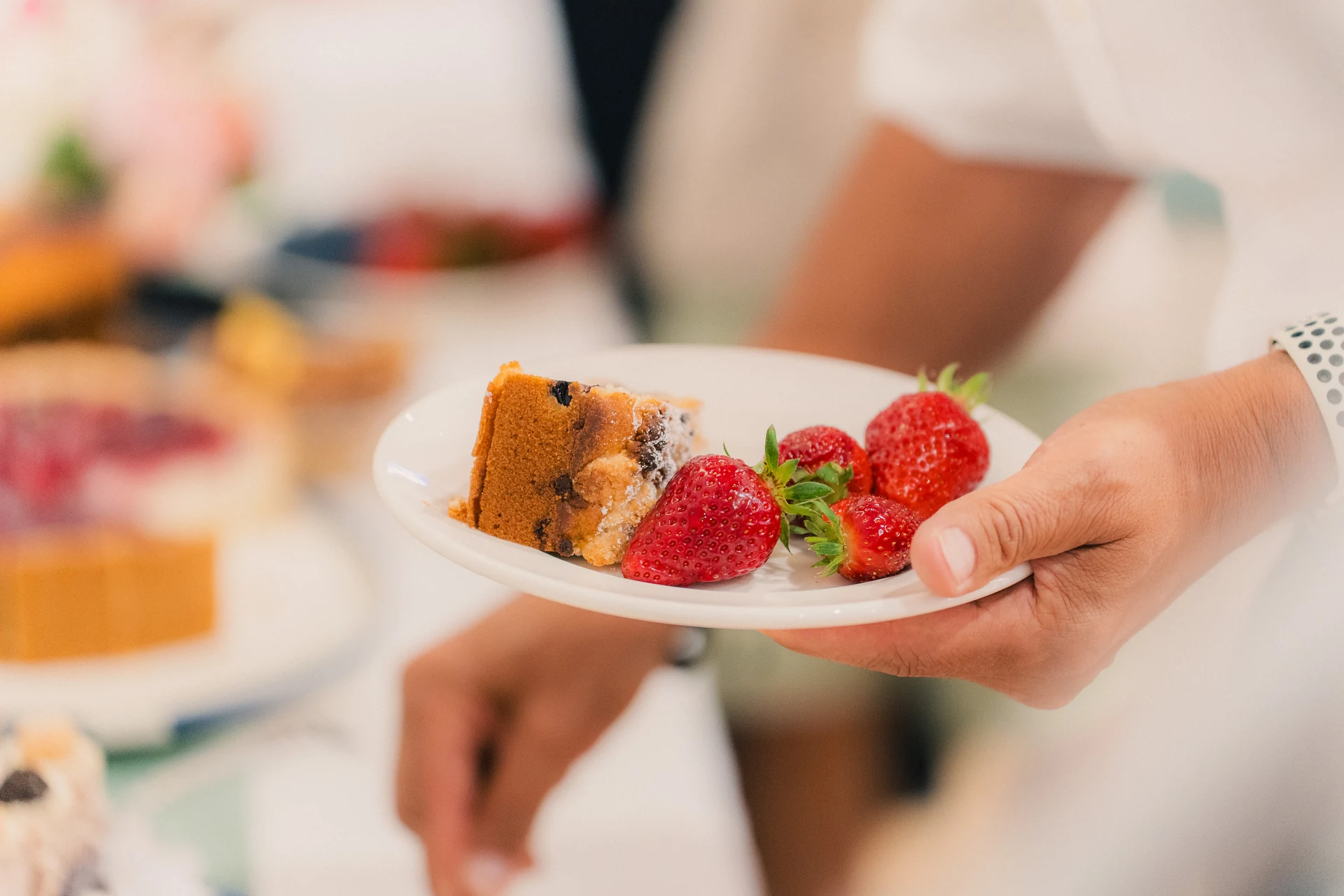 Ein Stück Kuchen mit Erdbeeren wird auf einem Teller gereicht