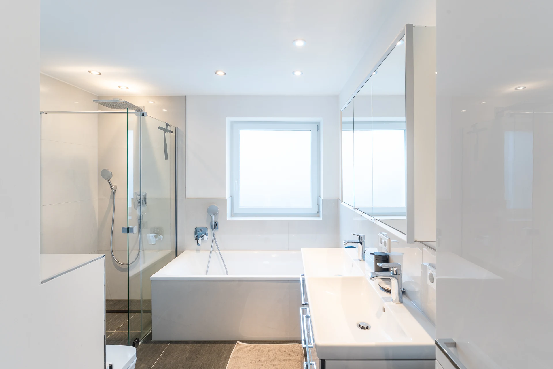Badezimmer mit Badewanne, Glasdusche und Waschtisch