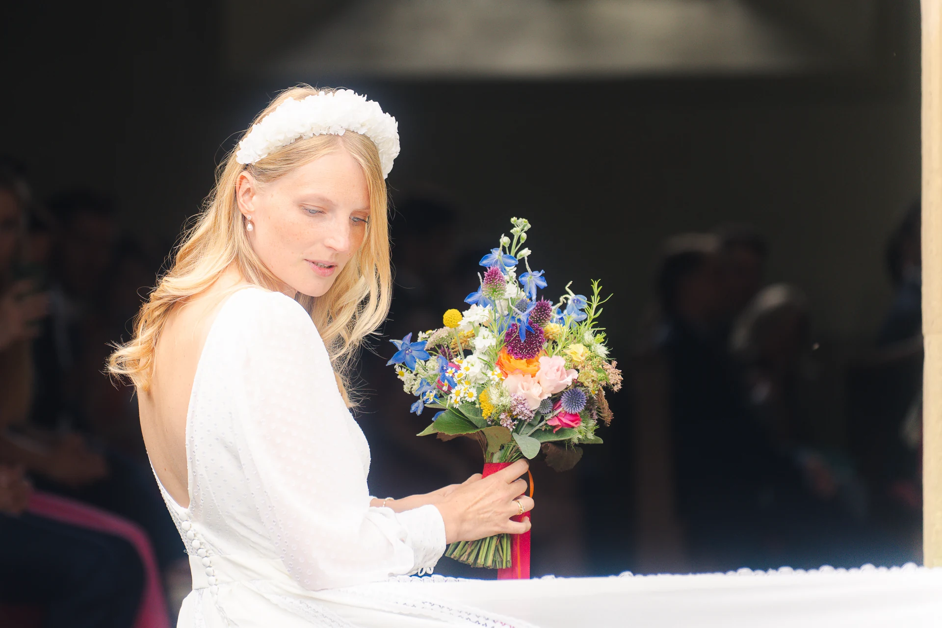 Die Braut im rückenfreien Kleid mit buntem Brautstrauß in der Kapelle