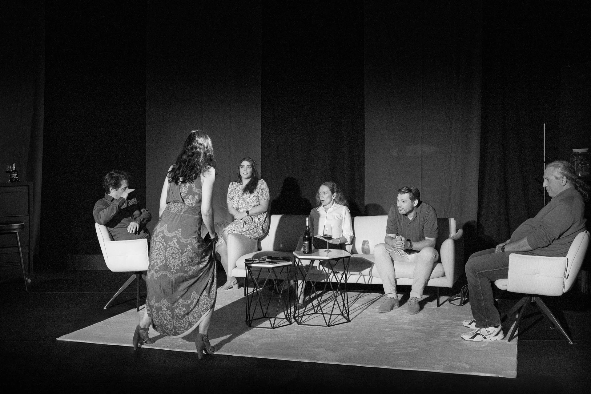 Schwarz-Weiß: das Ensemble in der Wohnzimmerkulisse, eine Schauspielerin steht in der Mitte