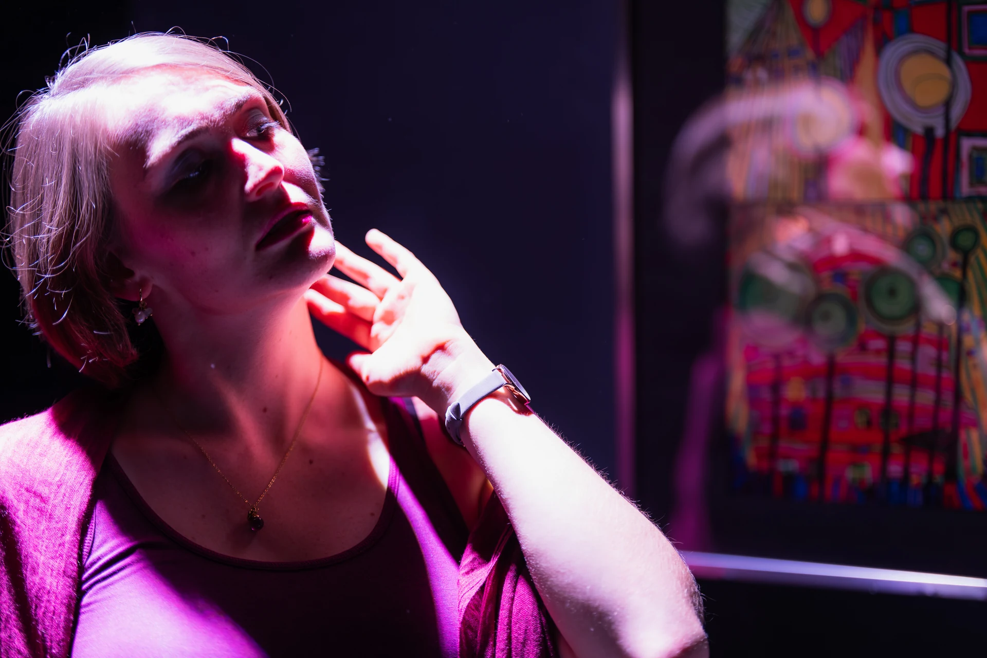 Schauspielerin im violetten Bühnenlicht, eine Hand am Hals